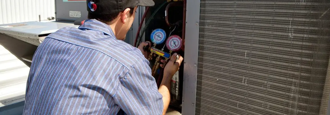 HVAC technician servicing a condenser unit in McDonough